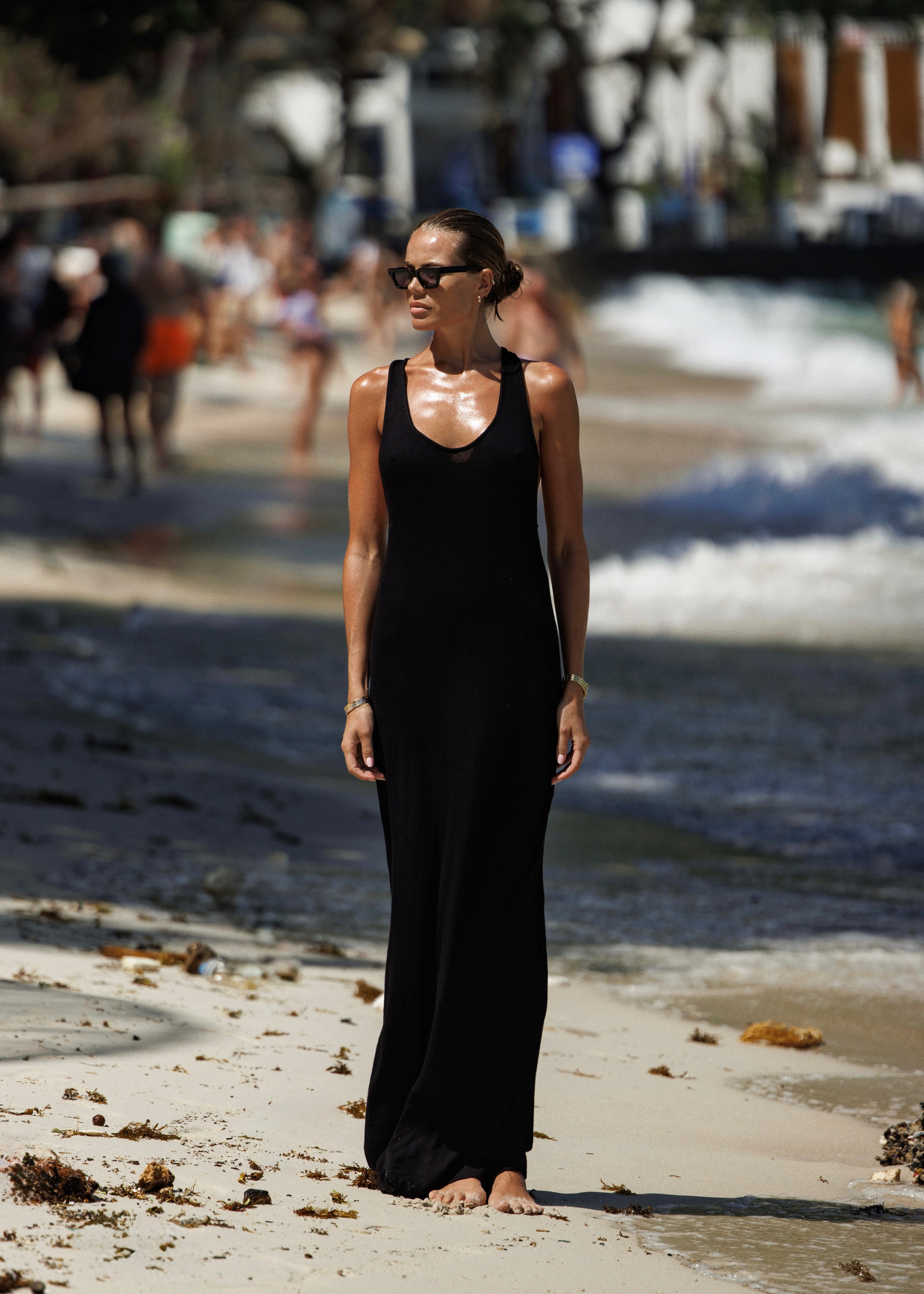 Woman in a black dailora dress standing on a beach with blurred background